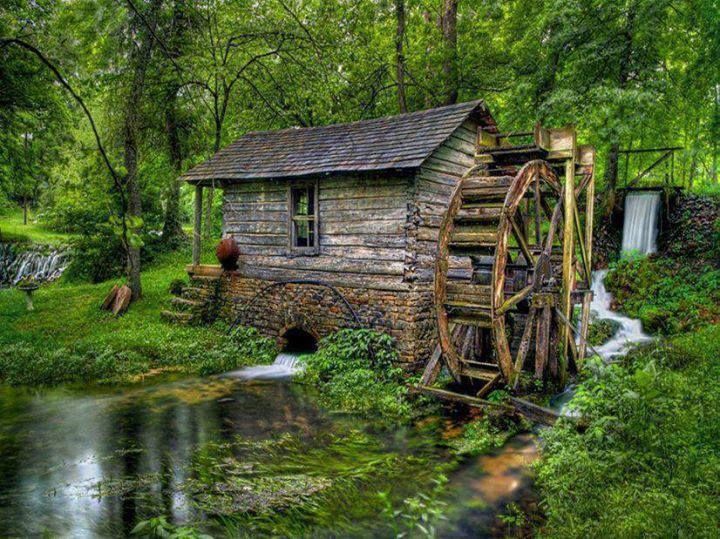 an old water mill next to a flowing river