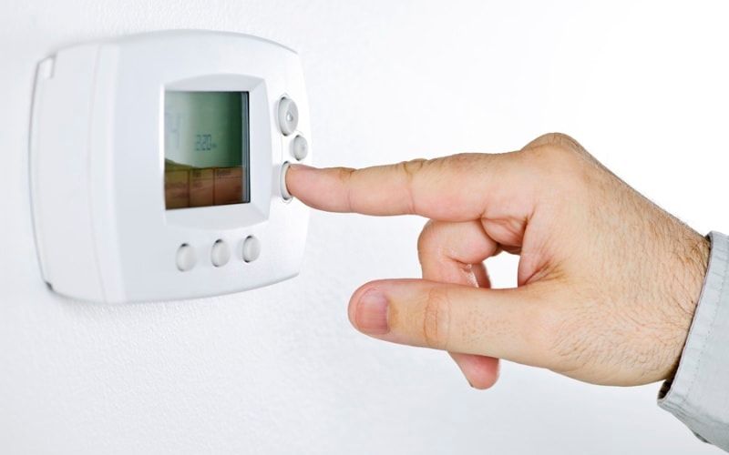 person adjusting programmable thermostat