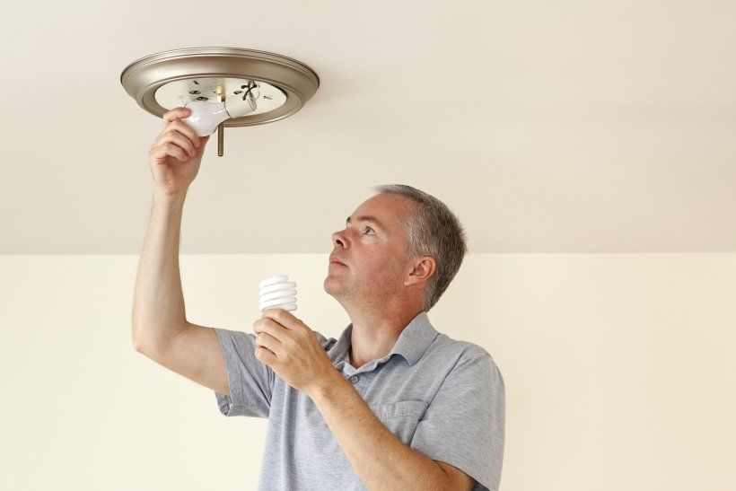 person changing a lightbulb to an led bulb