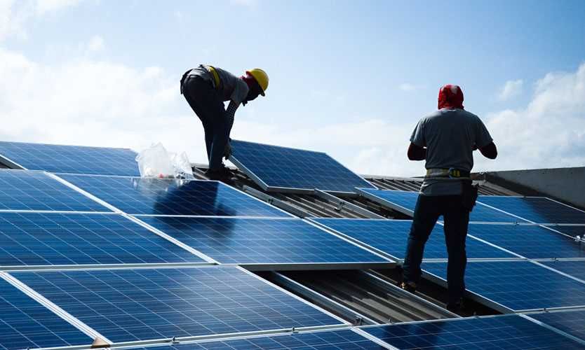 workers installing solar panels on a roof