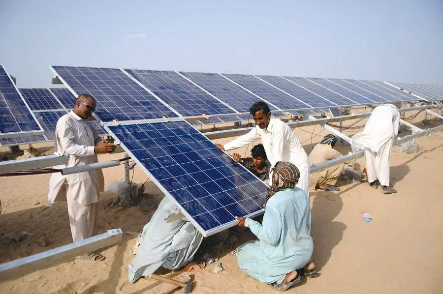 workers installing solar panels on the ground
