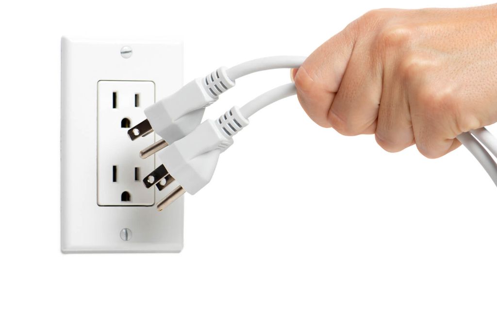 a person unplugging appliances and electronics when not in use to save electricity.