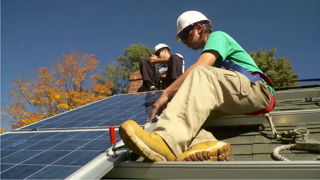 a person working on installing solar panels on a roof represents gaining hands-on experience through solar apprenticeships