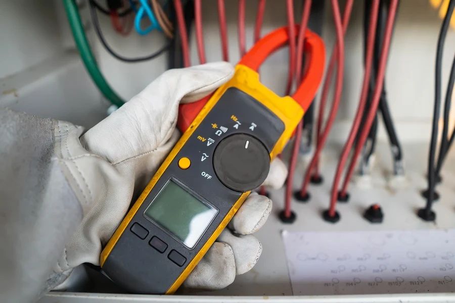 electrician using clamp meter to measure current.